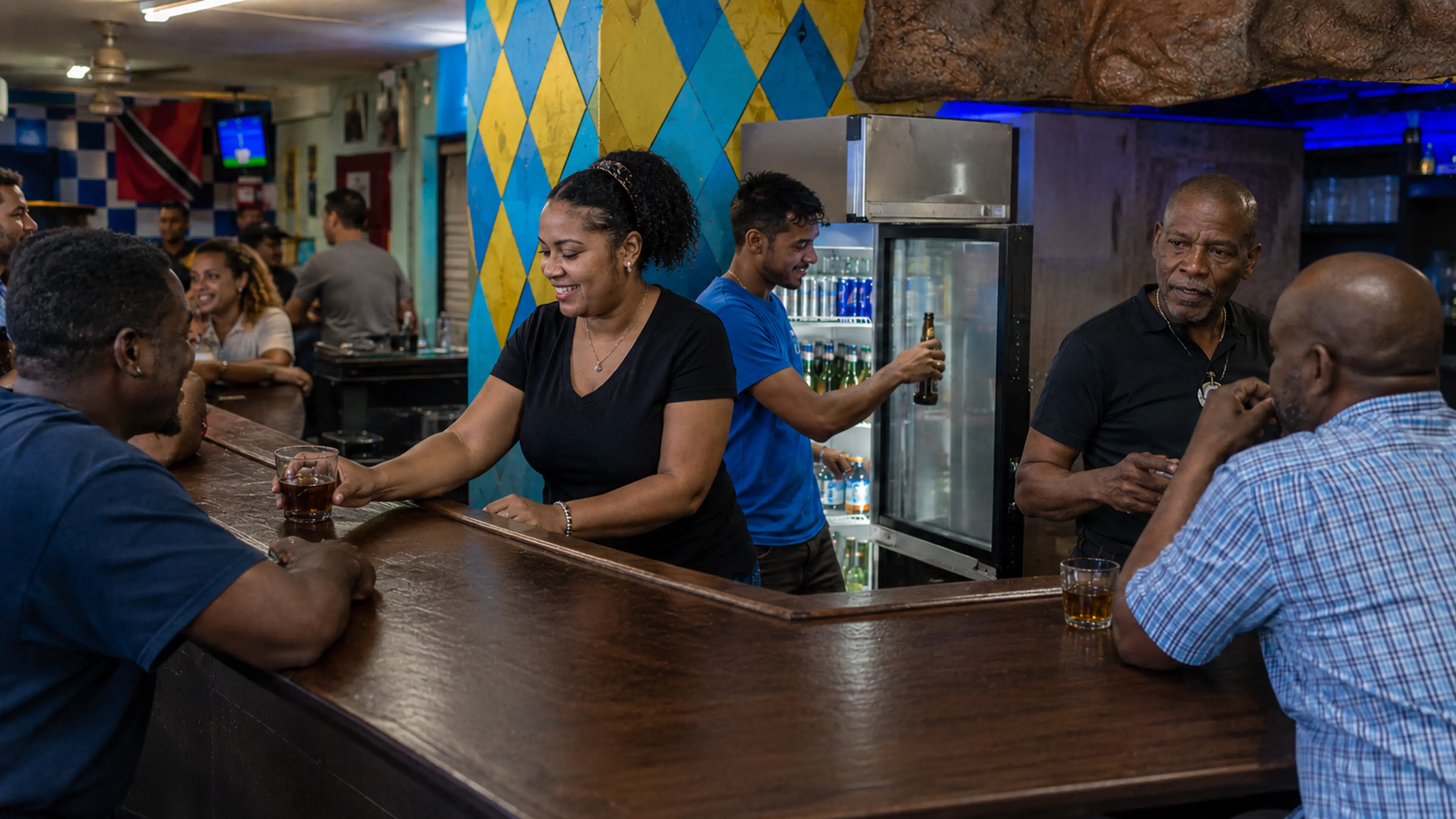 Workers serving customers behind a secure counter in a regular Trinidad bar